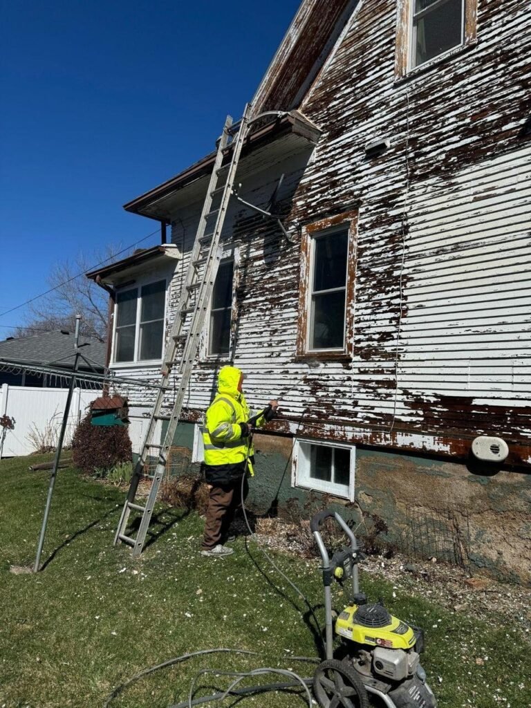 House painter preparing old exterior siding for painting in Sioux City, IA by Painting Pros