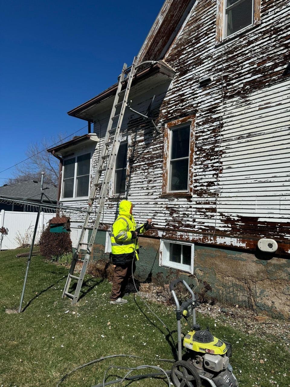 House painter preparing old exterior siding for painting in Sioux City, IA by Painting Pros